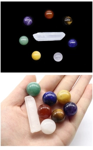 Detailed set of 7 chakra crystal spheres and clear quartz pillar held in palm for scale