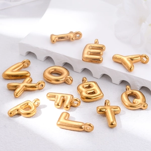 Detailed close-up of 3D gold alphabet pendants on white wavy decorative display