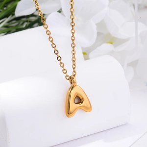Close-up of a 3D gold initial A pendant with polished mirror finish on a delicate chain