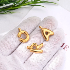 Macro detail of 3D gold stainless steel letter pendants C, A, and R for DIY jewelry