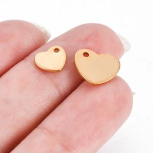 Makroaufnahme von Gold-Herzanhängern am Finger mit glatter Oberfläche und Größenunterschied