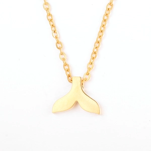 Gros plan d'un collier doré en acier inoxydable avec pendentif queue de poisson minimaliste