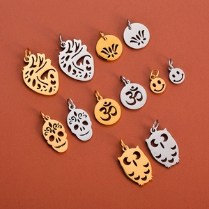 Close-up of polished stainless steel cutout pendants in heart, skull and owl shapes