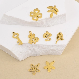 Gros plan de breloques dorées en acier inoxydable avec trèfle et rose pour bijoux
