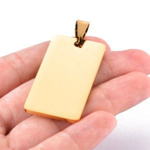Polished gold stainless steel rectangular tag pendant held for scale on white background