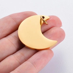 Polished gold crescent moon pendant charm for DIY jewelry being held by hand