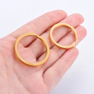 Flat stainless steel split key rings in gold finish shown in hand for size reference