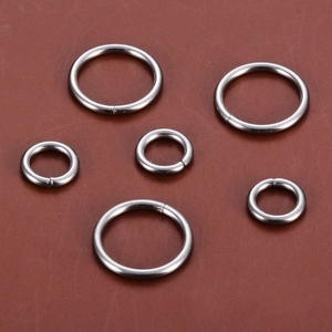 Polished stainless steel O-rings in three sizes on leather background for DIY bags and crafts