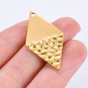 Handheld view of gold diamond-shaped pendant with smooth top and hammered bottom texture
