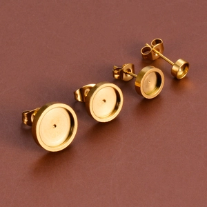 Close-up of four gold stainless steel stud earring bases with butterfly backings for DIY