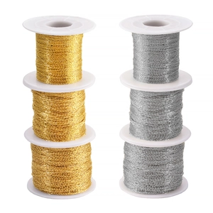 Detailed view of gold and silver rectangle cross chains wound on white spools for DIY jewelry