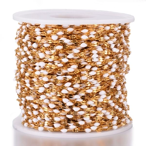 Macro detail of gold plated stainless steel chain roll with white enamel beads for DIY