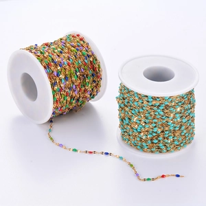 Golden stainless steel chains with colorful enamel beads wound on white spools for DIY jewelry