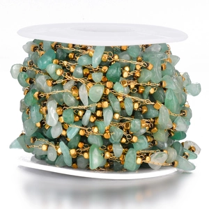 Detail of bohemian gold bead chain with green natural stone chips on white spool