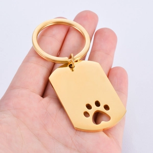 Golden stainless steel mirror-finish dog paw cutout pet tag keychain held in hand