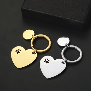 Close-up of polished gold and silver heart-shaped keychains with cutout paw print design