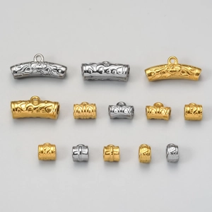 Detalle de cuentas tubulares de acero inoxidable talladas y conectores para joyas artesanales