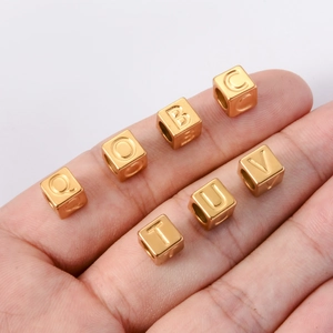 Macro view of 7mm golden square alphabet beads with engraved letters for DIY jewelry