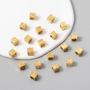 Detailed macro view of 7mm square gold stainless steel letter beads for DIY jewelry making