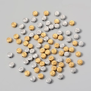 Macro detail of 7mm titanium steel alphabet beads in gold and silver for DIY jewelry making