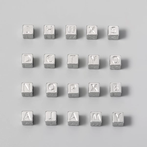 Macro view of 7mm titanium steel alphabet cube beads in a neat matrix for DIY jewelry