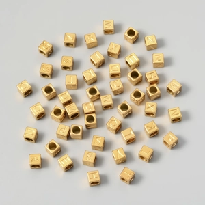 Macro shot of gold cube beads with engraved letters for DIY necklace and bracelet crafting