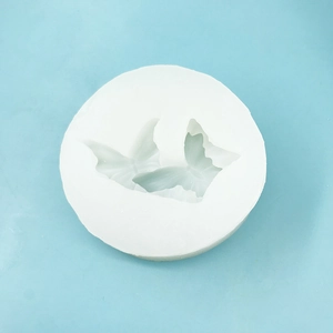 Detail view of round white silicone mold featuring two butterfly shaped 3D cavities