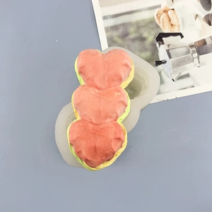 Close-up of triple heart silicone mold for baking with pink heart-shaped cake detail