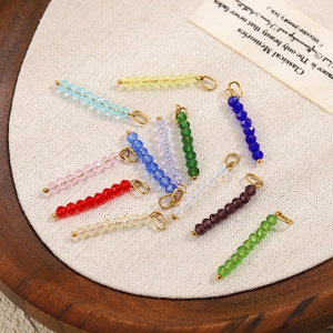 DIY colorful crystal bead pendants with golden rings displayed on a rustic wooden tray