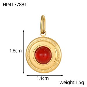 Macro shot of 1.4cm round gold stainless steel pendant with red gemstone and embossed edge