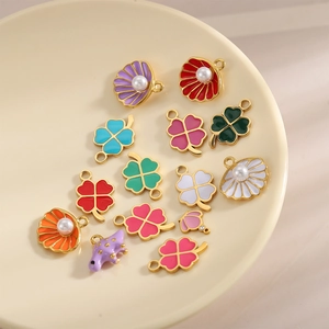 Detail view of colorful enamel fruit and clover charms in a beige tray for DIY jewelry