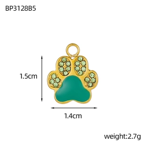 Detailed view of a gold paw pendant with green enamel and crystals, 1.5cm by 1.4cm size