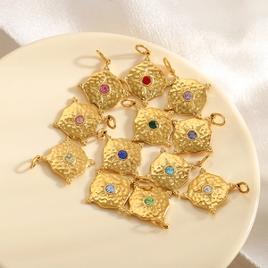 Textured gold square pendants with colorful rhinestones on a ceramic jewelry tray