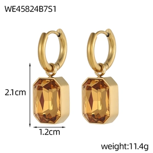 Elegante gouden druppeloorbellen met amberkleurige glaskristallen op witte achtergrond