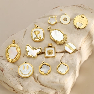 Elegante goldene Edelstahl-Anhänger mit weißer Muscheleinlage auf Naturstein-Hintergrund