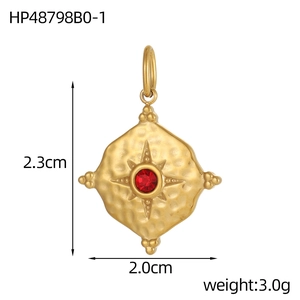 Detail view of a vintage gold oval pendant with hammer texture and red gemstone center