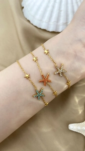 Close-up of golden starfish bracelets with colorful rhinestones on a silk background