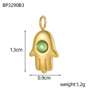 Detailed view of a gold Hamsa Hand pendant with a green crystal, measuring 1.3cm by 0.9cm