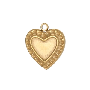 Détail macro d'un pendentif cœur en acier inoxydable doré avec des bords à texture pointillée