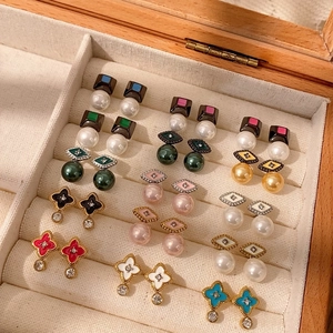 Variedad de pendientes de esmalte y perlas bañados en oro de 18K en un joyero de madera