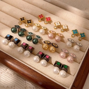 Detalle de pendientes de flores y formas geométricas en esmalte de colores y oro