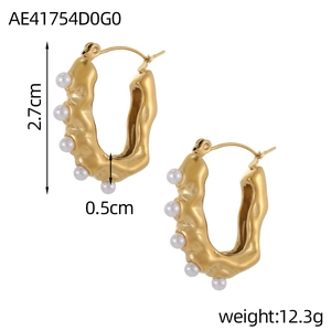 Detail view of gold C-shape earrings with irregular lava texture and white pearls