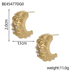 Detail view of gold C-shaped earrings with celestial moon star patterns and small pearls
