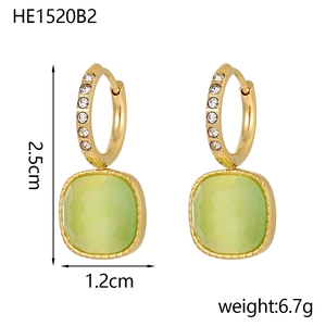 Detail view of gold earrings with cubic zirconia and pale green cat eye stone drops