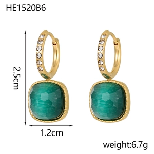 Detail view of gold earrings with cubic green gems and white crystal stones