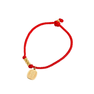Detail eines roten geflochtenen Armbands mit goldener Glücksbringer-Gravur auf Anhänger