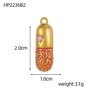 Macro view of gold capsule pendant with pink rhinestone and red enamel pattern