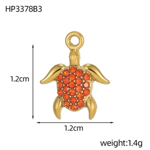 Detailed macro of gold sea turtle pendant with orange rhinestones and 1.2cm size measurement