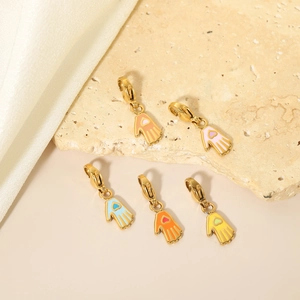 Five gold-plated Hamsa charms with colorful enamel hearts and lobster clasps on silk fabric