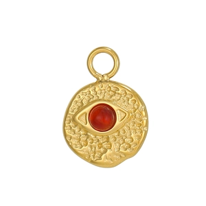 Detailed close-up of a bohemian evil eye pendant featuring red stone and hammered gold finish